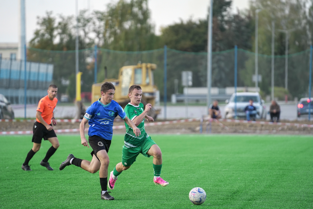 Zawodnik Unii Tarnów biegnie z piłką obok gracza Okocimskiego Brzesko.